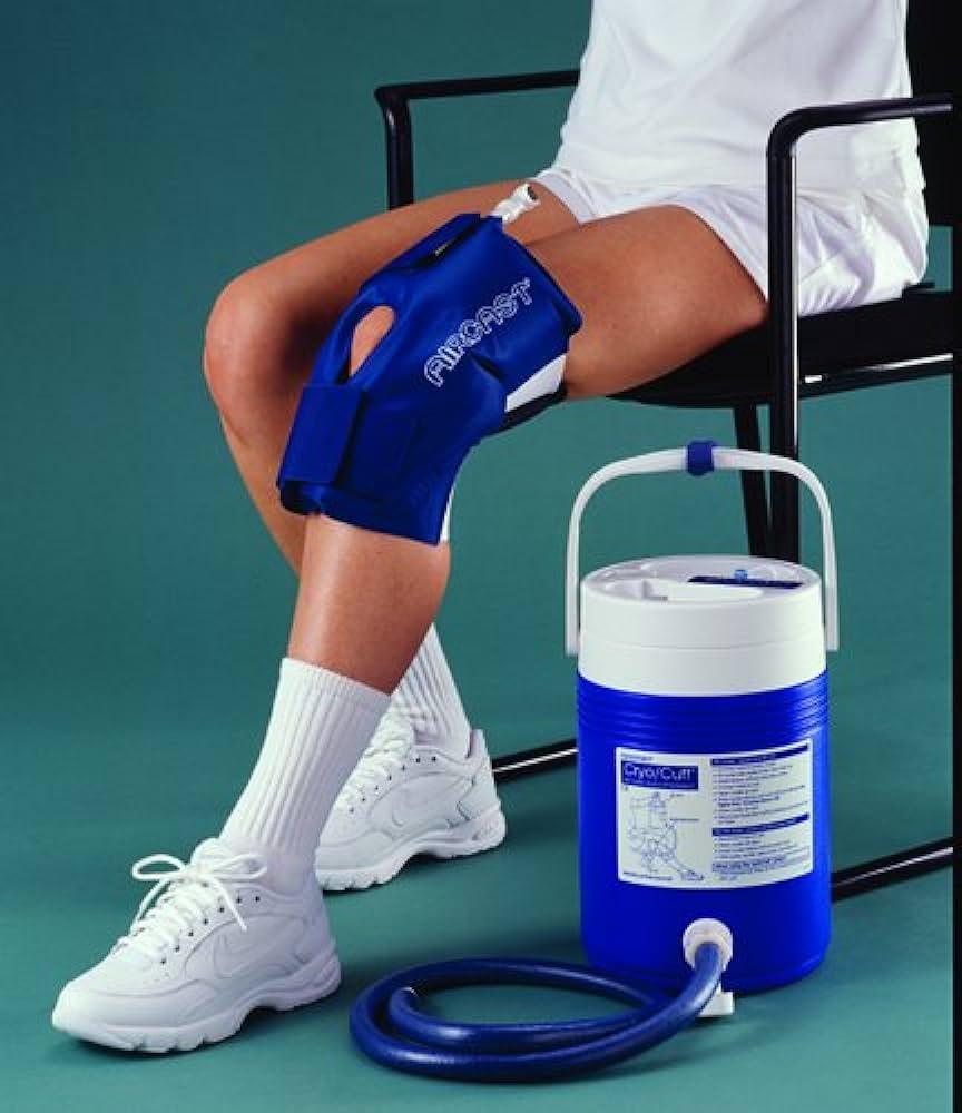 Person seated with Aircast Cryo Cuff cold therapy device on knee next to blue cold therapy machine