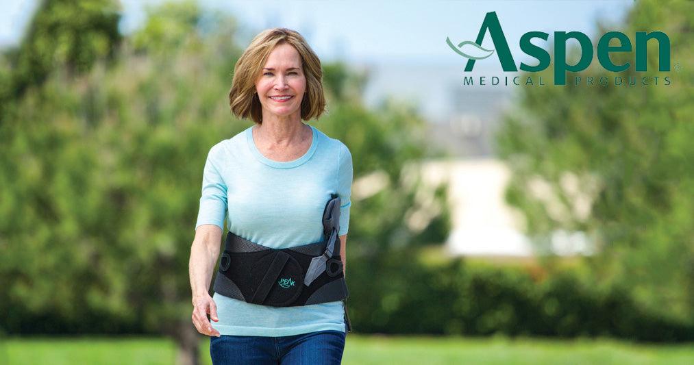 Smiling woman outdoors wearing Aspen back brace for support from Supply Cold Therapy
